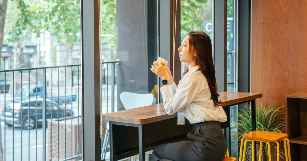 カフェでコーヒーを飲んで外を眺める女性