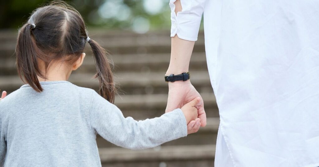子どもと手を繋いで歩く後ろ姿