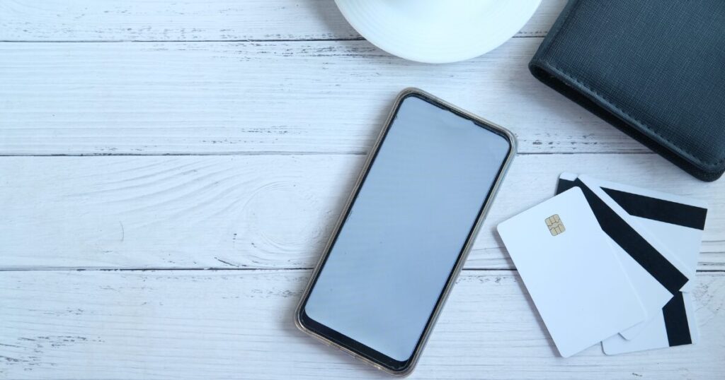 デスクの上に並べられたスマホ、クレジットカード、財布