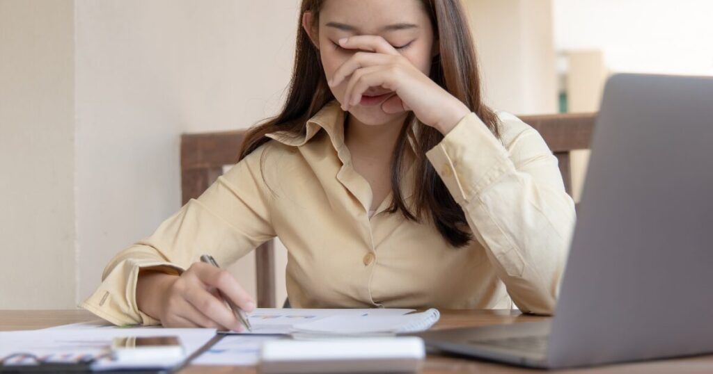 資料を見ながら頭を抱えて悩む女性